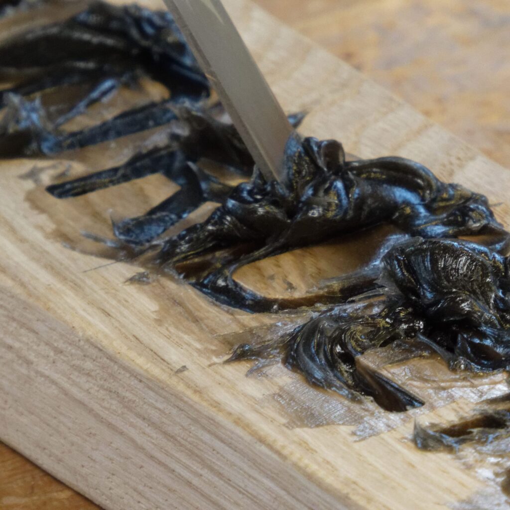 Mit einem Schmalspachtel wird der getönte DRY FLEX® 4 Holzspachtel sorgfältig in die Reparaturstelle gedrückt, um Lufteinschlüsse zu vermeiden.