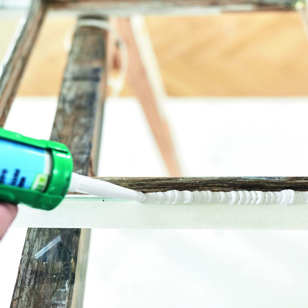 Ein Repair Care Anwender trägt Fensterkitt DRY SEAL™ MP an einem historischen Fenster auf.