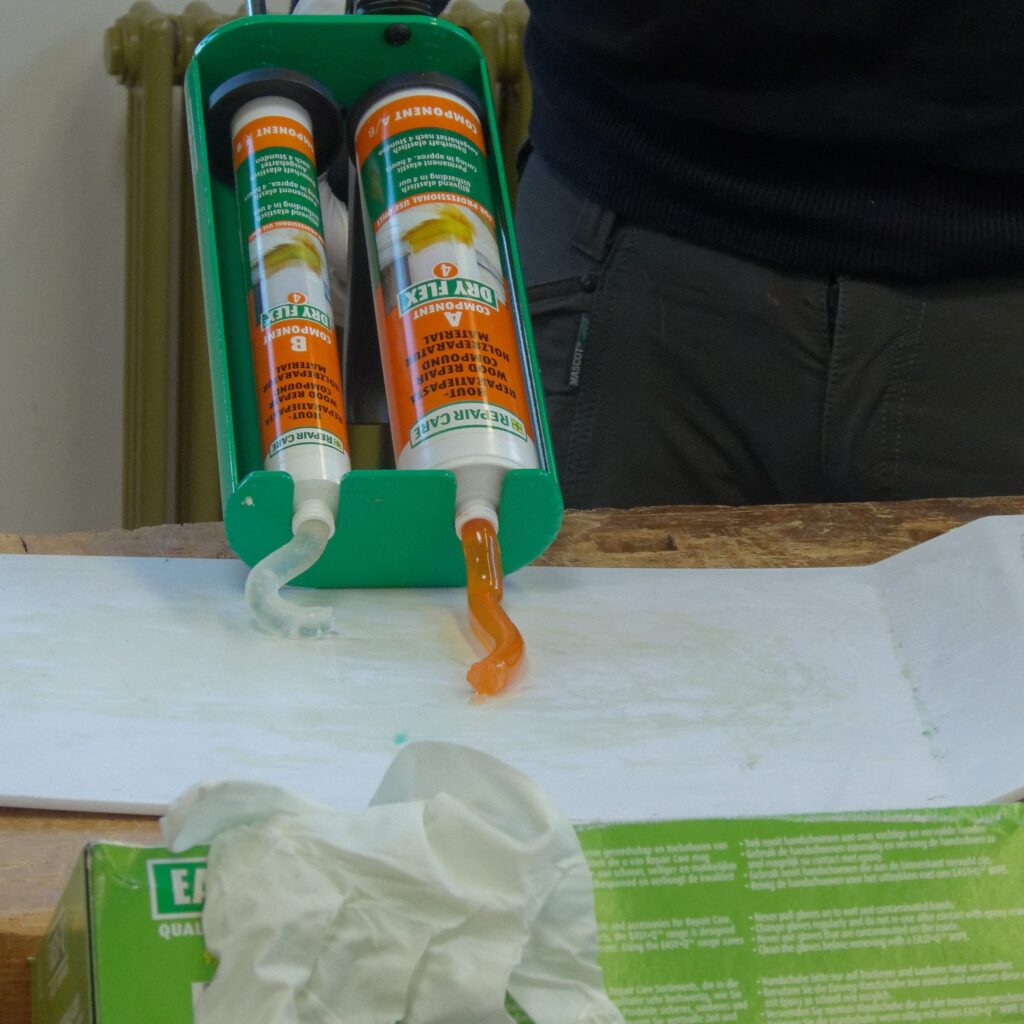 Zweikomponentiger DRY FLEX® 4 Holzspachtel wird aus einer Doppelkartusche auf ein Mischbrett ausgepresst.