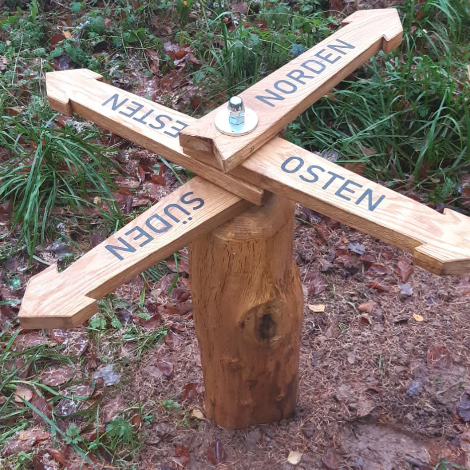 Eingetönter DRY FLEX® 4 Holzspachtel füllt Holzpfeile, die die Richtung auf dem Wanderweg angeben