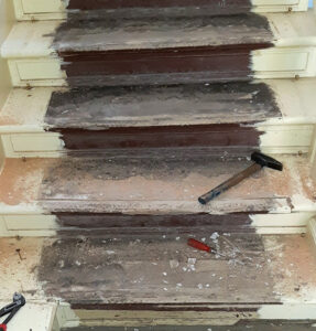 Eine alte, beschädigte Holztreppe mit stark abgenutzten Stufen wird für eine anstehende Reparatur vorbereitet.