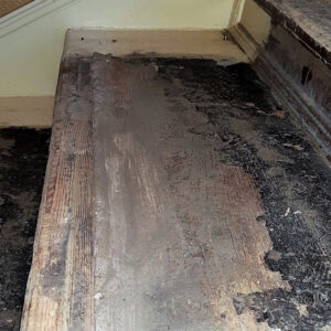 Eine alte, beschädigte Holztreppe mit stark abgenutzten Stufen und Leimresten wird für eine anstehende Reparatur vorbereitet